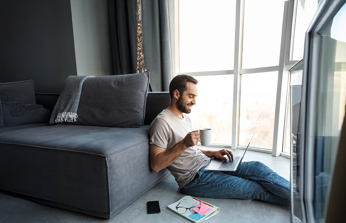 Home jove estudiat amb portàtil a casa